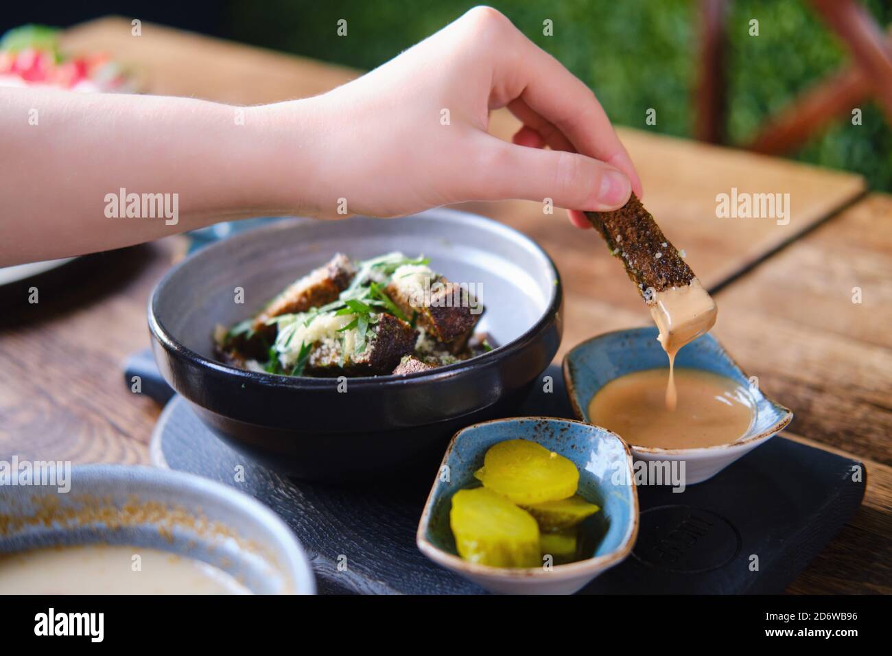 La mano inumidisce i crostini di pane di segale in un succo, primo piano Foto Stock