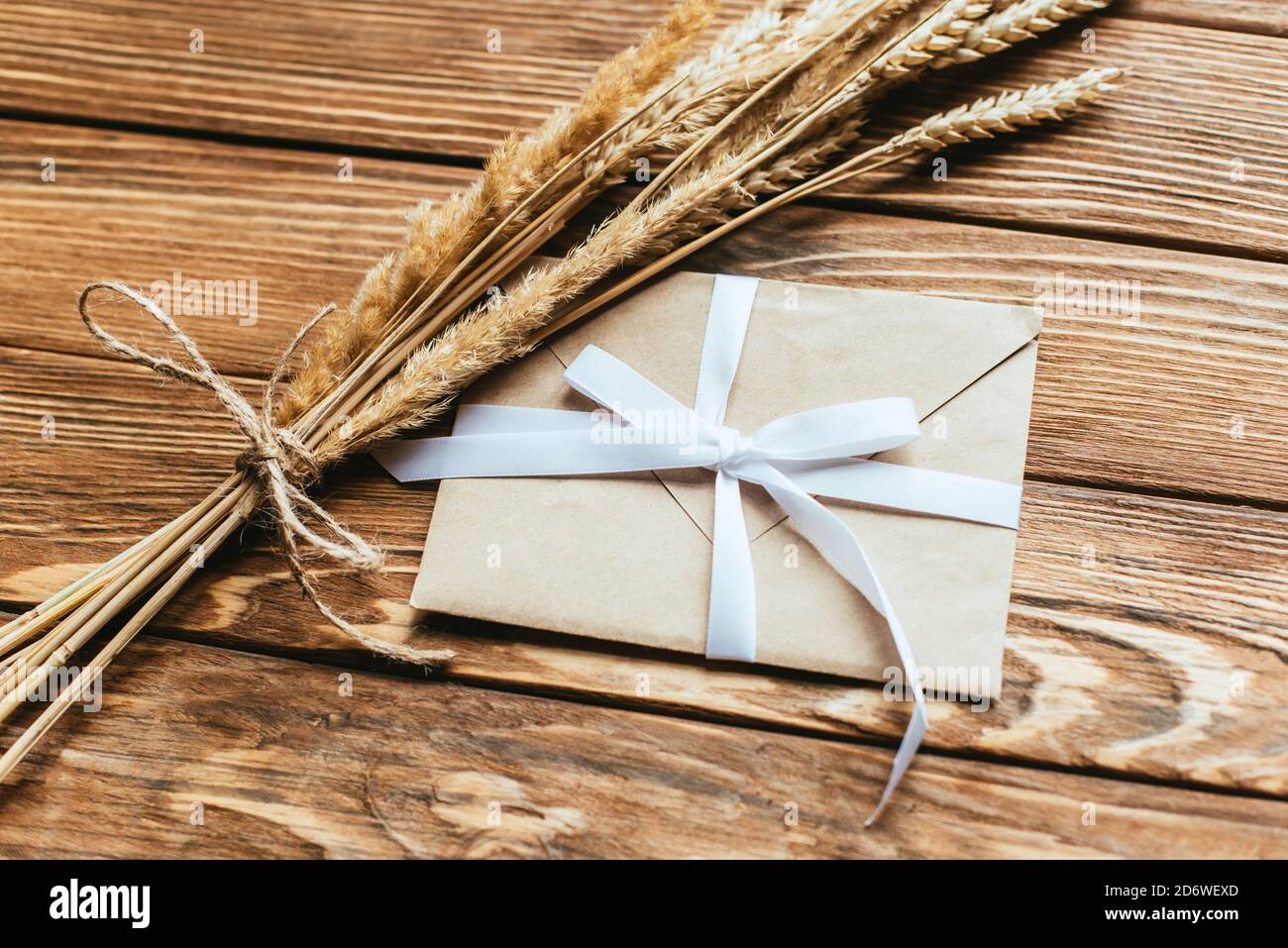 busta con prua vicino alle orecchie di grano su sfondo di legno Foto Stock