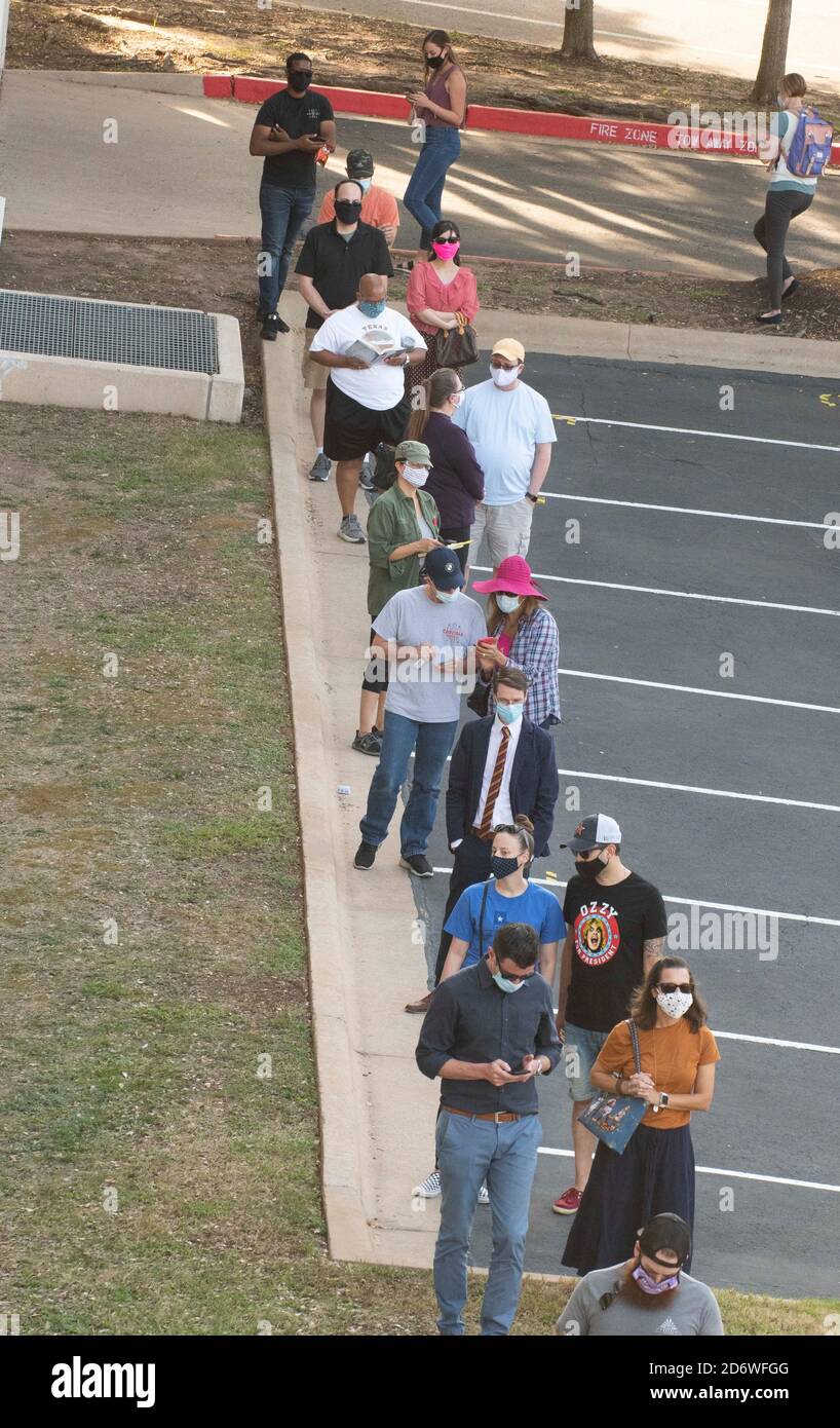 Austin, Texas USA, ottobre 13 2020: I texani mascherati attendono pazientemente in fila nella zona di Arboretum nel nord di Austin in un sito di voto precoce per lanciare i voti nelle elezioni presidenziali del 2020. I funzionari riportano un numero record di elettori in anticipo con quasi 40,000 al giorno in tutta la città. Foto Stock