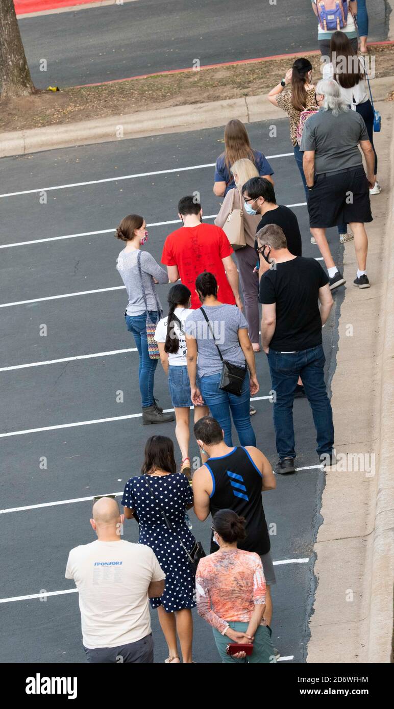 Austin, Texas USA, ottobre 13 2020: I texani mascherati attendono pazientemente in fila nella zona di Arboretum nel nord di Austin in un sito di voto precoce per lanciare i voti nelle elezioni presidenziali del 2020. I funzionari riportano un numero record di elettori in anticipo con quasi 40,000 al giorno in tutta la città. Foto Stock