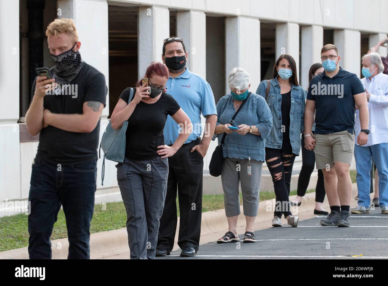 Austin, Texas USA, ottobre 13 2020: I texani mascherati attendono pazientemente in fila nella zona di Arboretum nel nord di Austin in un sito di voto precoce per lanciare i voti nelle elezioni presidenziali del 2020. I funzionari riportano un numero record di elettori in anticipo con quasi 40,000 al giorno in tutta la città. Foto Stock