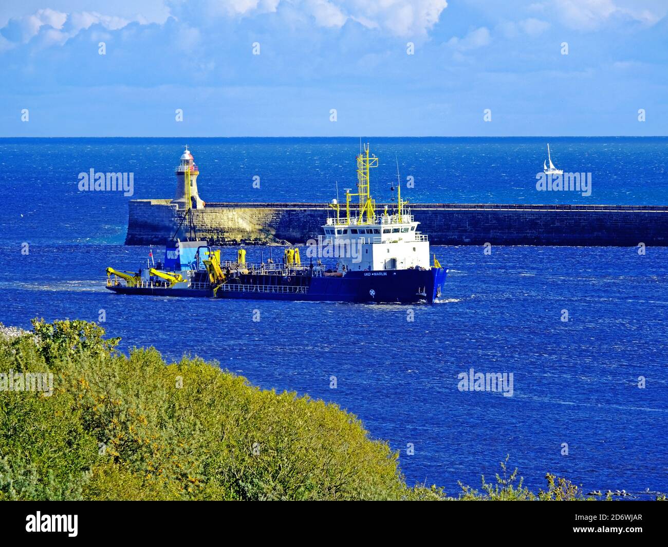 UKD Marlin dragare un canale nella bocca del fiume Tyne con cielo blu e barca a vela Foto Stock