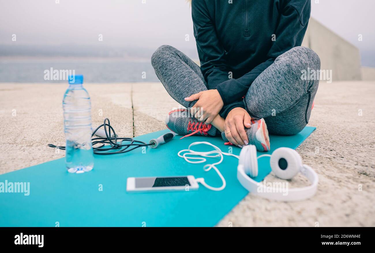 Sezione bassa della donna seduta con accessori sportivi Foto Stock