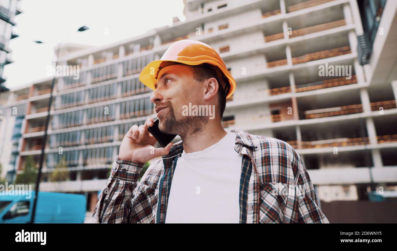 Tecnico che parla al telefono. Architetto utilizzando il telefono sul cantiere. Processo di controllo delle chiamate telefoniche dei caposquadra. Comunicazioni dei lavoratori edili in Foto Stock