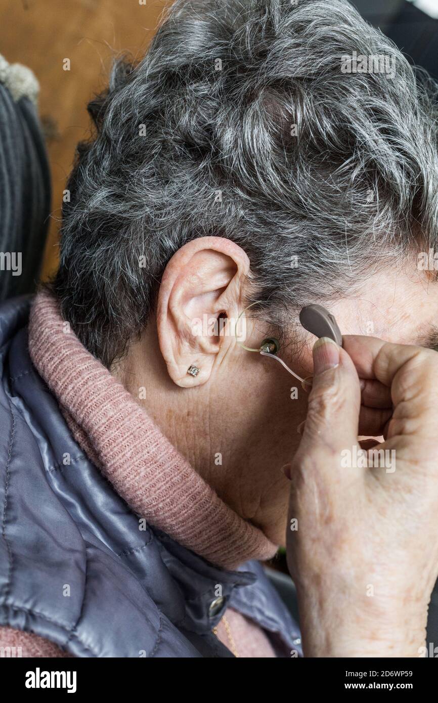 Donna anziana tenendo gli apparecchi acustici. Foto Stock