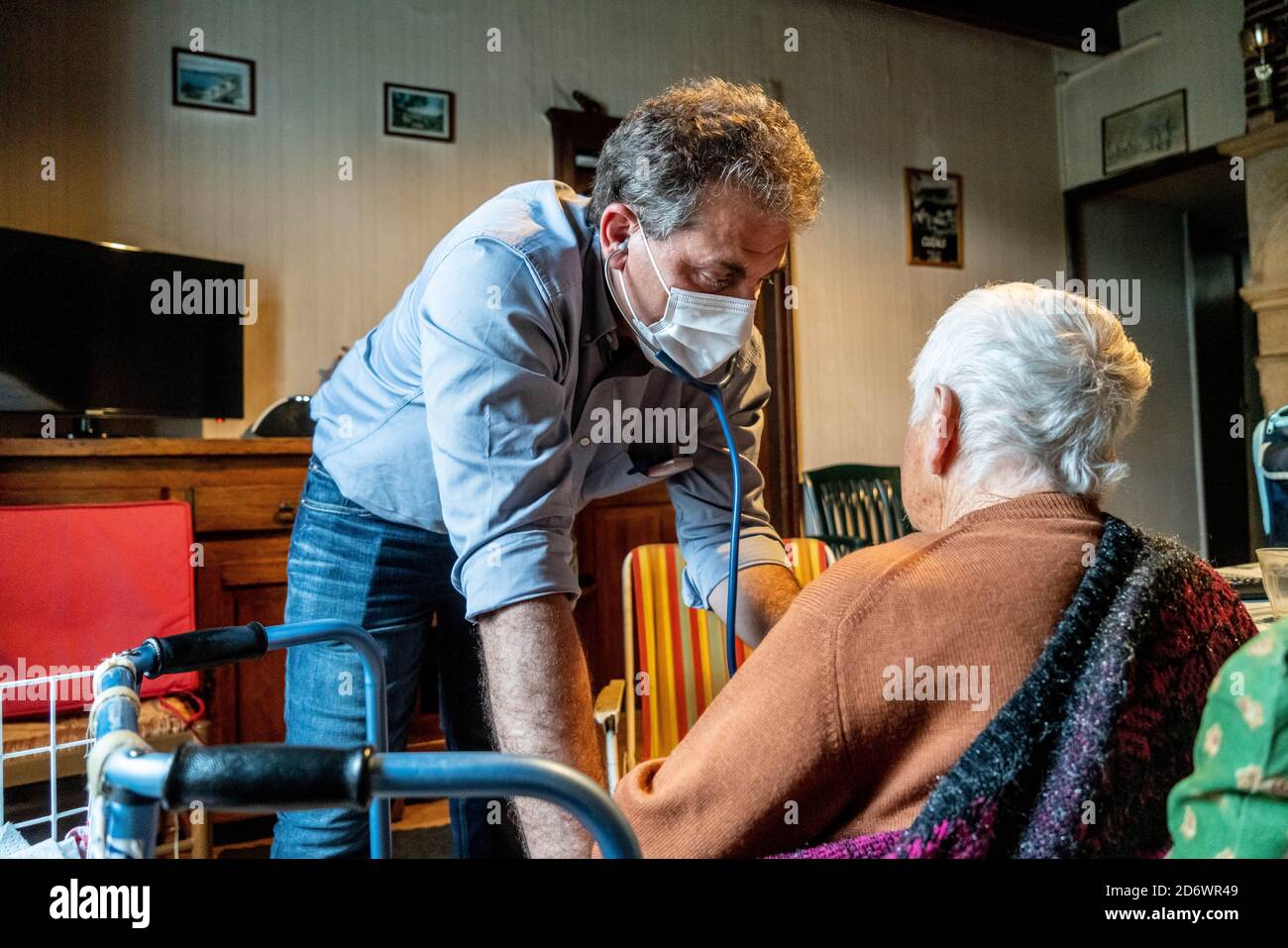Medico generico che indossa una maschera chirurgica, con paziente a casa, Francia, giugno 2020. Foto Stock