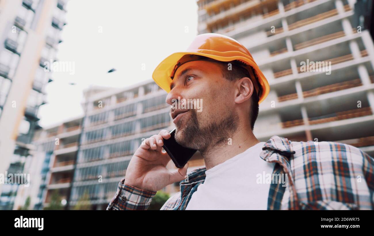 Tecnico che parla al telefono. Architetto utilizzando il telefono sul cantiere. Processo di controllo delle chiamate telefoniche dei caposquadra. Comunicazioni dei lavoratori edili in Foto Stock