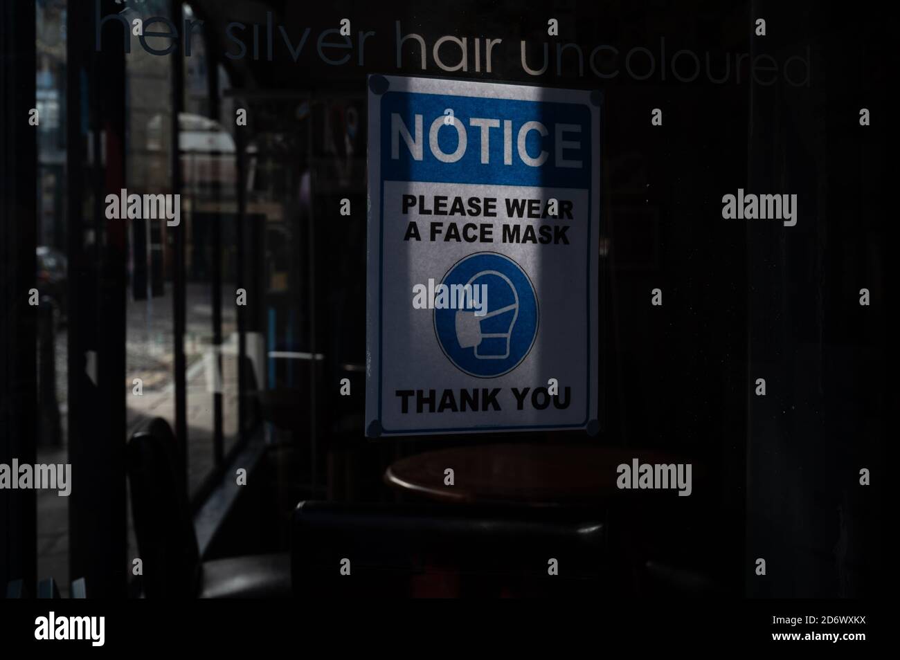 Si prega di indossare una maschera di avviso all'interno della finestra del caffè Foto Stock