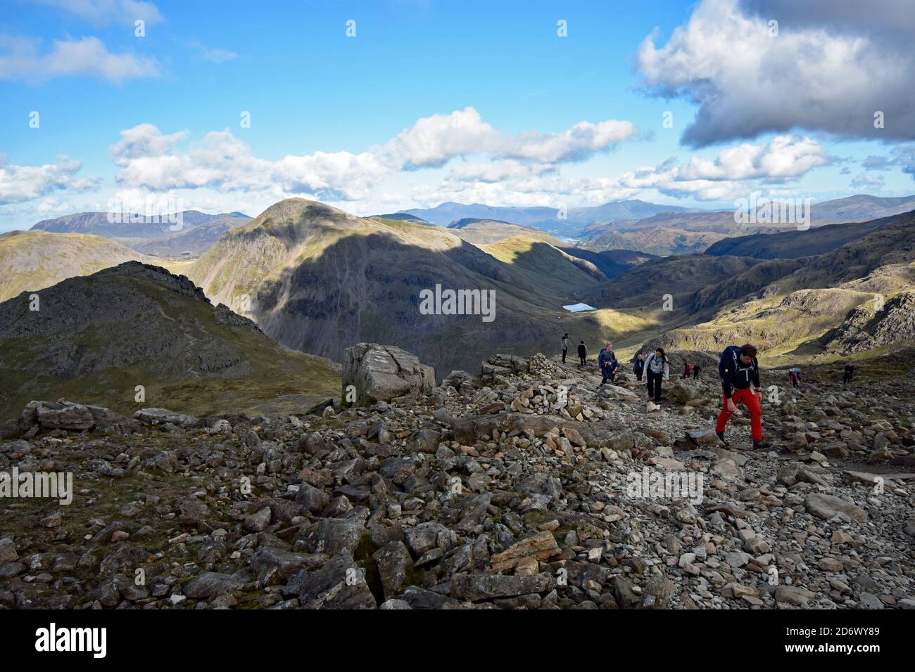 Gli escursionisti di sesso maschile e femminile lottano fino all'ultima parte del percorso fino all'altopiano roccioso di Scafell Pike nel Lake District National Park, Inghilterra. Foto Stock