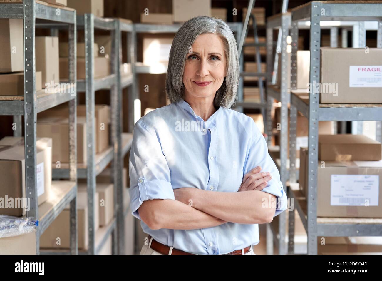 Responsabile donna anziana sicuro in piedi in consegna magazzino di spedizione, ritratto. Foto Stock