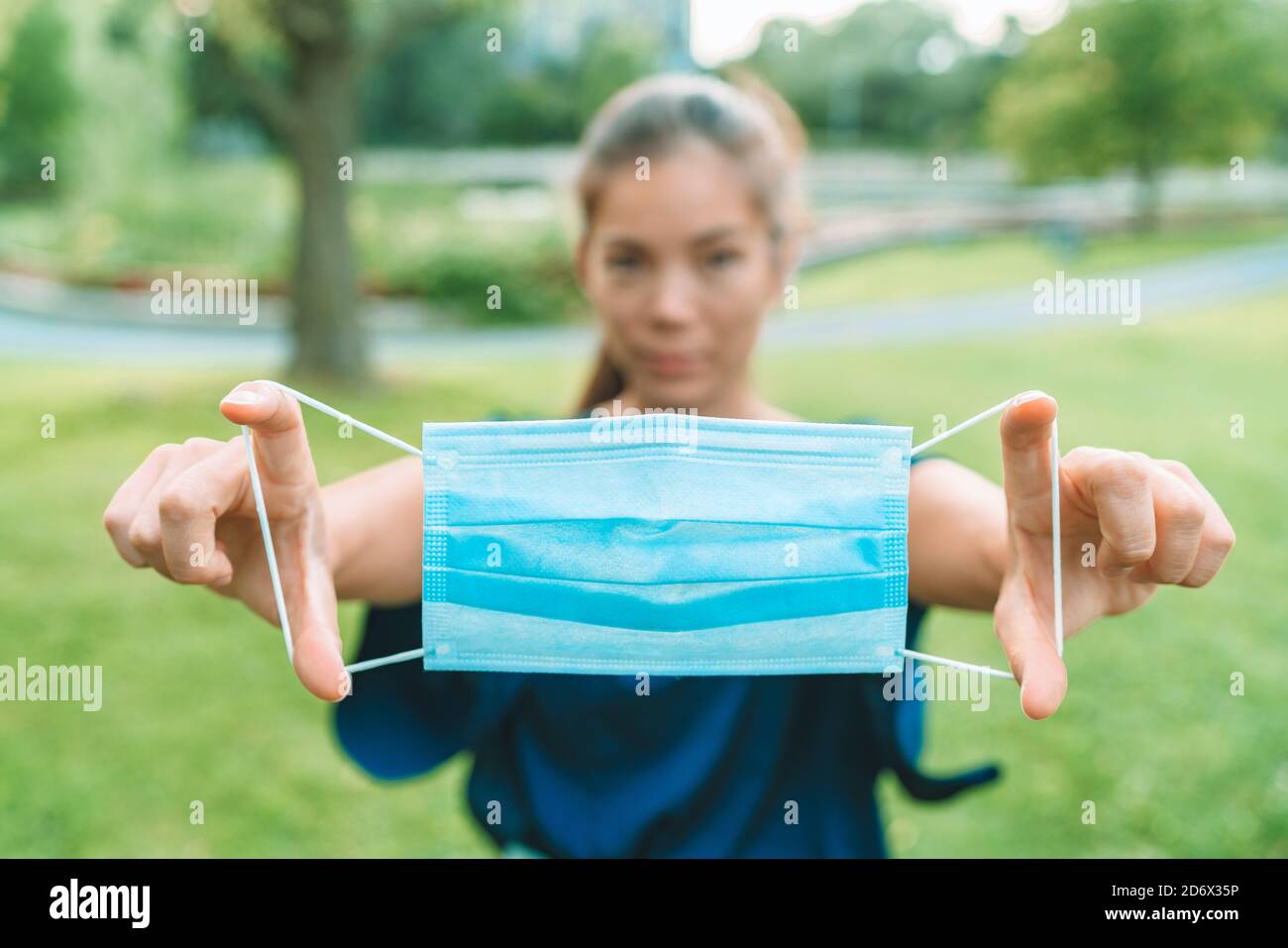 Maschera chirurgica per la copertura del viso obbligatoria in città. Donna che regge DPI protettivi per il coronavirus Foto Stock