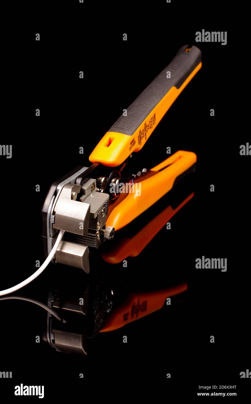 Utensile professionale per la terminazione di cavi per spelatura dell'isolamento isolato sul sfondo nero riflettente Foto Stock