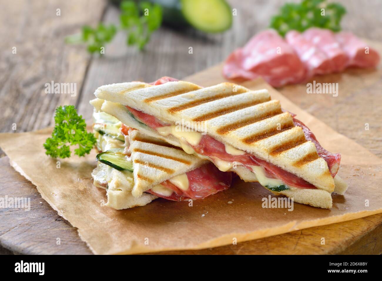 Doppio panino pressato e tostato con salame e formaggio italiano servita su carta sandwich su un tavolo di legno Foto Stock