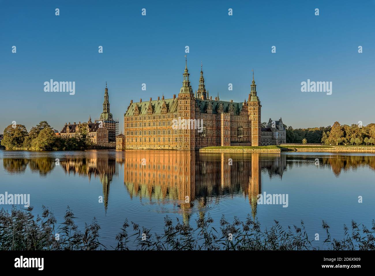 Il castello di Frederiksborg riflette nel lago una mattina senza vento al sole e un gabbiano nuoterà in acqua, Hillerød, Danimarca, 17 ottobre 2020 Foto Stock