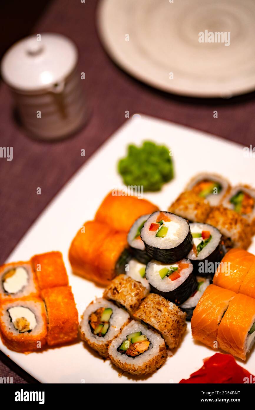 Serve appetitosi sushi su piatto bianco nel cafe. Primo piano di gustosi panini di sushi con wasabi e zenzero nel ristorante tradizionale giapponese. Foto Stock