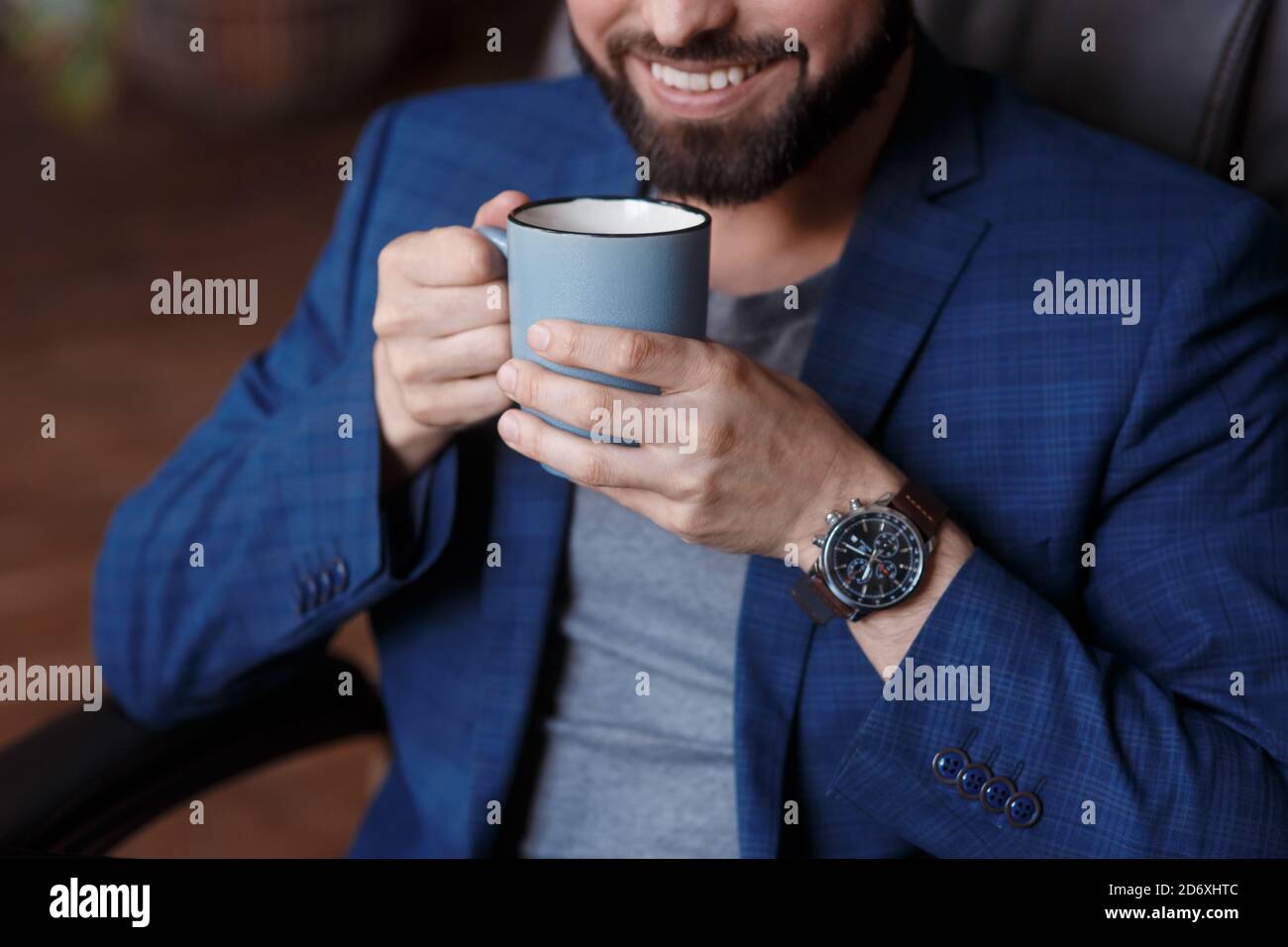 Primo piano mano di un giovane uomo d'affari sorridente in una tazza di caffè Foto Stock