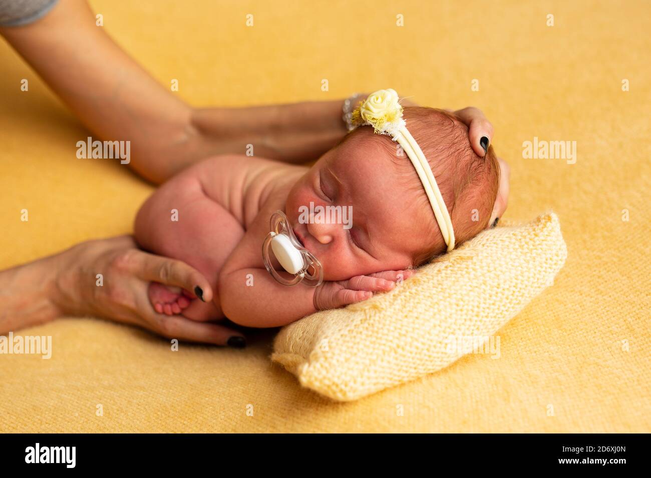 Preparazione per la fotografia del concetto del neonato, carino bambino nato con un bendaggio sulla testa, con le mani del fotografo Foto Stock