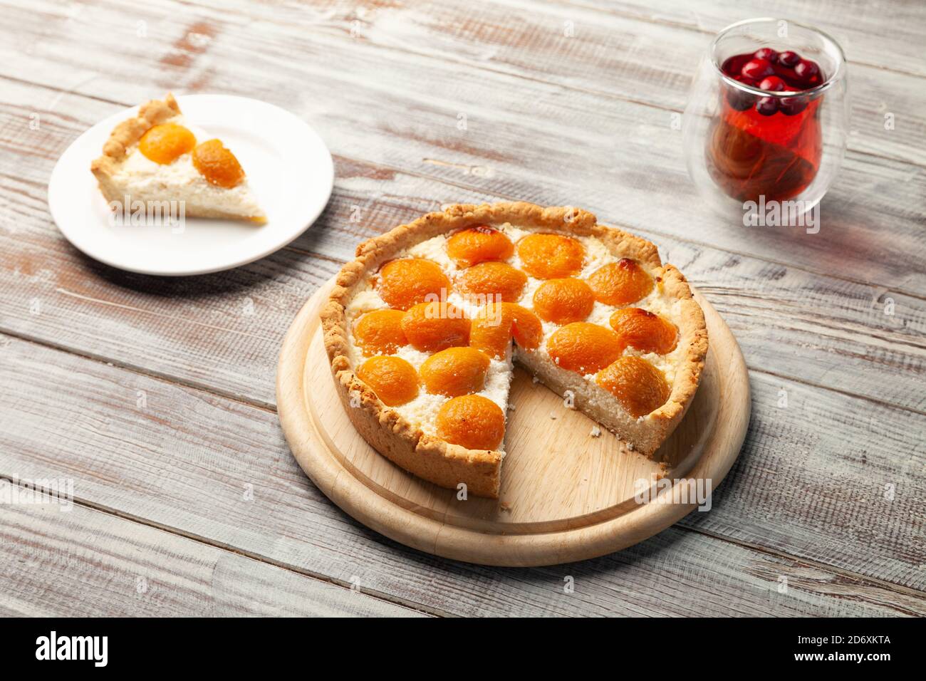 Cheesecake di pesca fatta in casa, tazza di tè alle bacche, pezzo di torta vicino sul piatto Foto Stock
