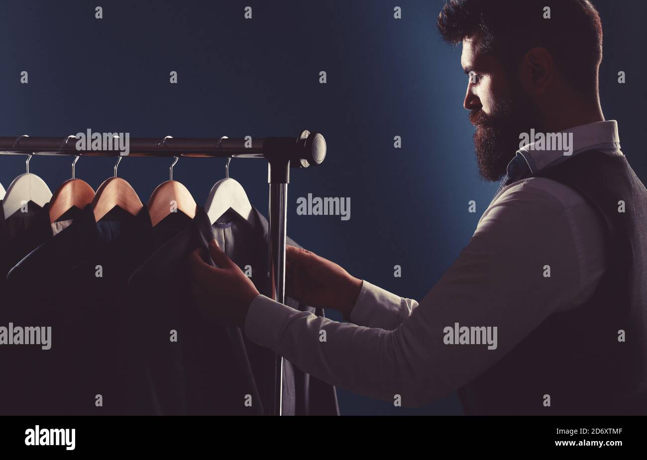 Su misura. Abito da uomo, sarto nella sua officina. Eleganti abiti da uomo appesi in fila. Abiti classici da uomo di lusso su rack in eleganti da uomo Foto Stock