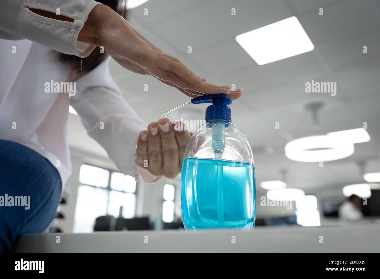 Metà della sezione di uomo d'affari che sanitizza le sue mani in ufficio Foto Stock