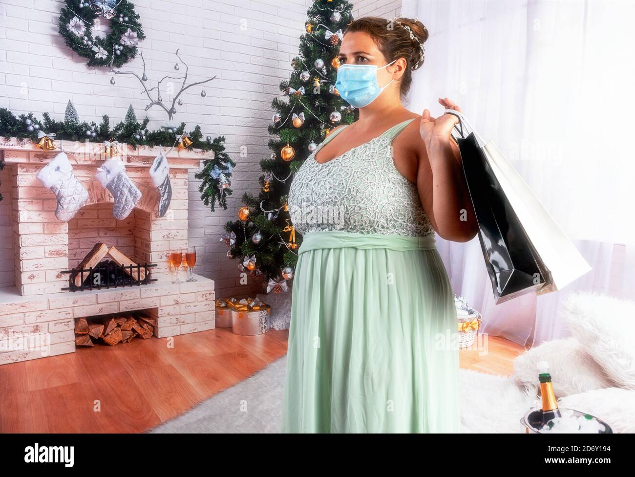 Una donna sovrappeso, elegante con una maschera e campane in mano suona la campana per i regali in Covid 19 volte. Foto Stock