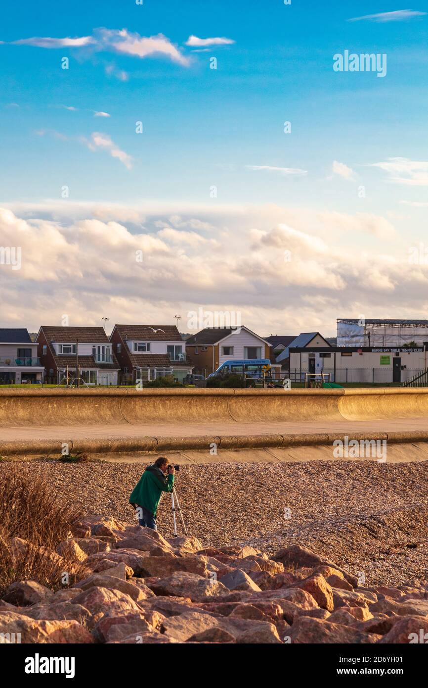 Un fotografo attende il tramonto con la sua macchina fotografica su un treppiede, Hampton, Herne Bay, Kent, UK Foto Stock