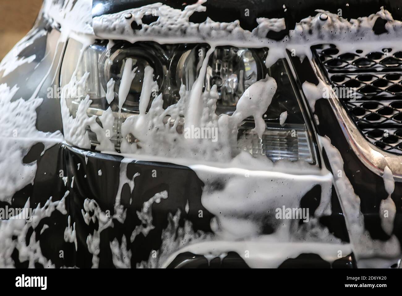 Autolavaggio. Schiuma di shampoo sul paraurti dell'auto. Foto Stock