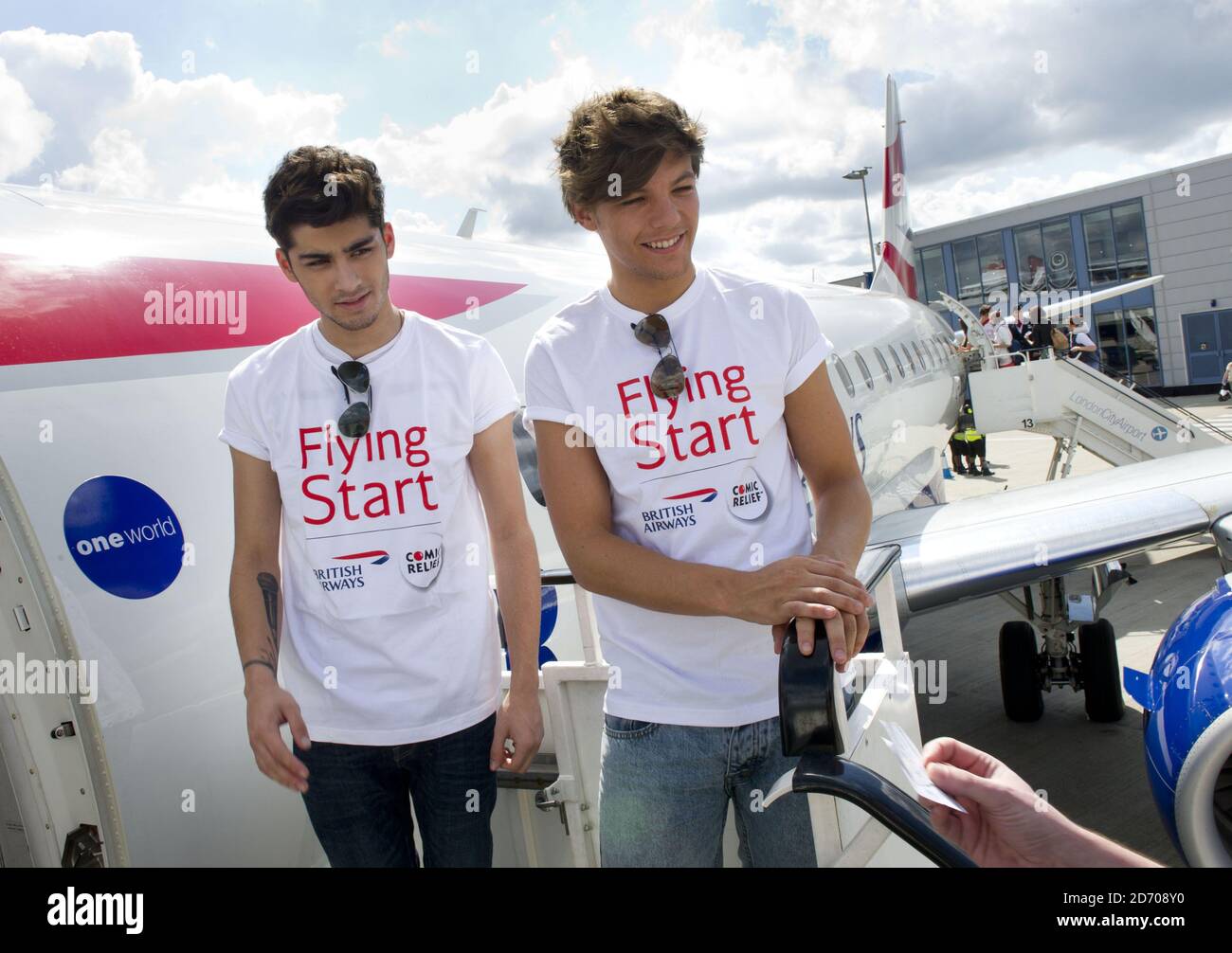 Zayn Malik (l) e Louis Tomlinson di una direzione raffigurati a bordo del volo BA1D - un volo charter privato da Londra a Manchester, ospitato dalla band per i vincitori della competizione, che ha raccolto Â£50,000 per Flying Start - la partnership di beneficenza di British Airways con Comic Relief. Foto Stock