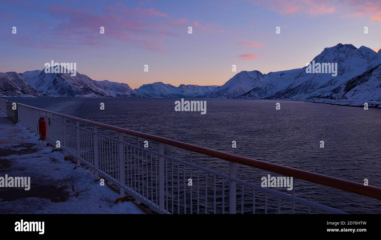 Vista invernale dell'oceano artico e delle montagne innevate dal ponte superiore di una nave da crociera vicino a Øksfjord, Norvegia, Scandinavia alla luce della sera. Foto Stock