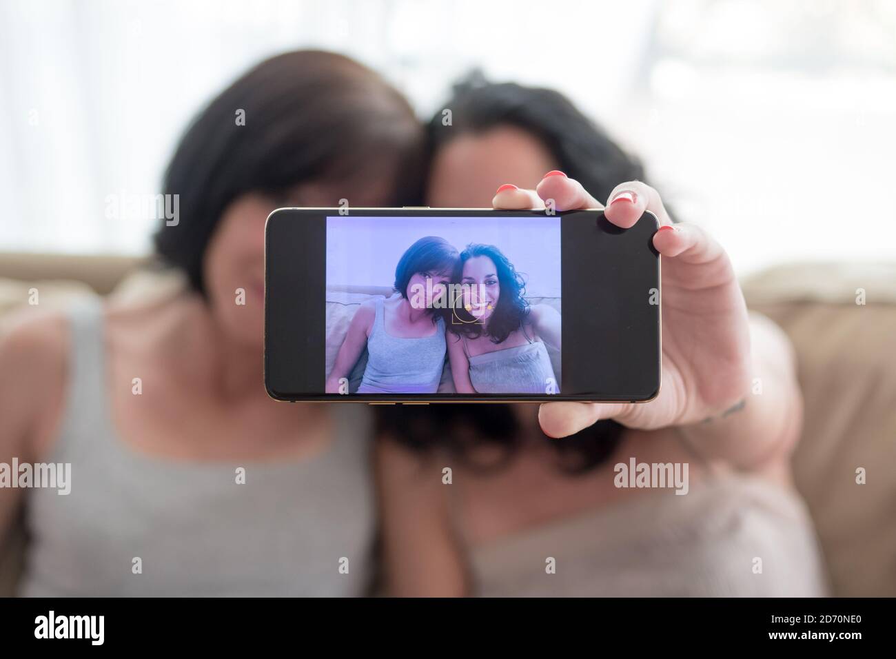 due giovani donne si divertono e ridono mentre si prende un selfie con i loro telefoni Foto Stock