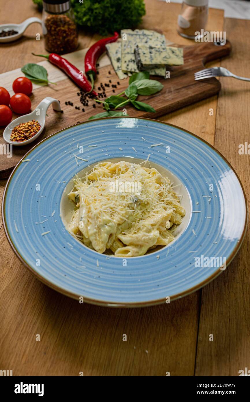 Penne Quatro Formaggi su tavolo di legno con ingredienti accanto it.Italian food. Foto Stock