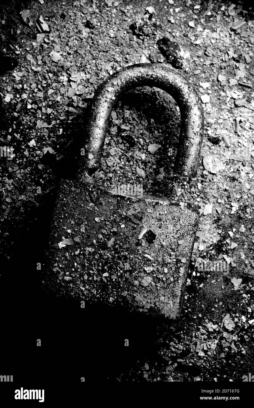 Un vecchio lucchetto rotto arrugginito sepolto in cenere Foto Stock