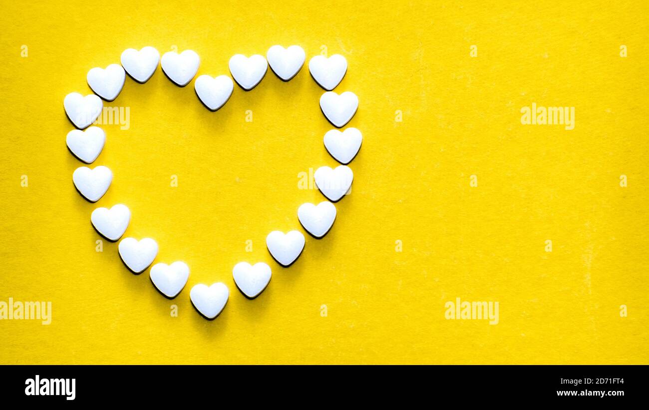 Compresse a forma di cuore che formano una forma a cuore su un giallo sfondo Foto Stock