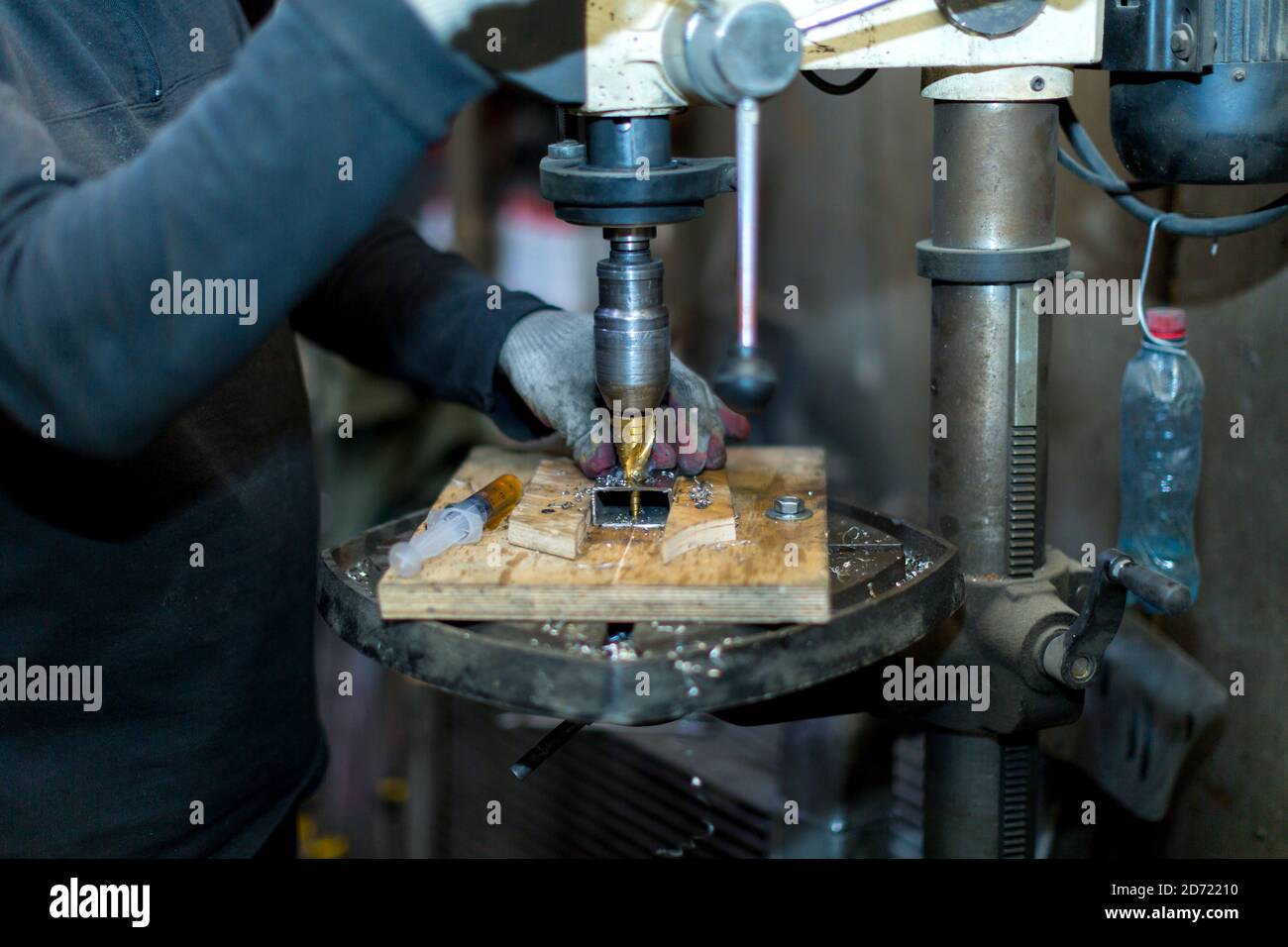 Un lavoratore perfora una parte su una macchina di perforazione Foto Stock