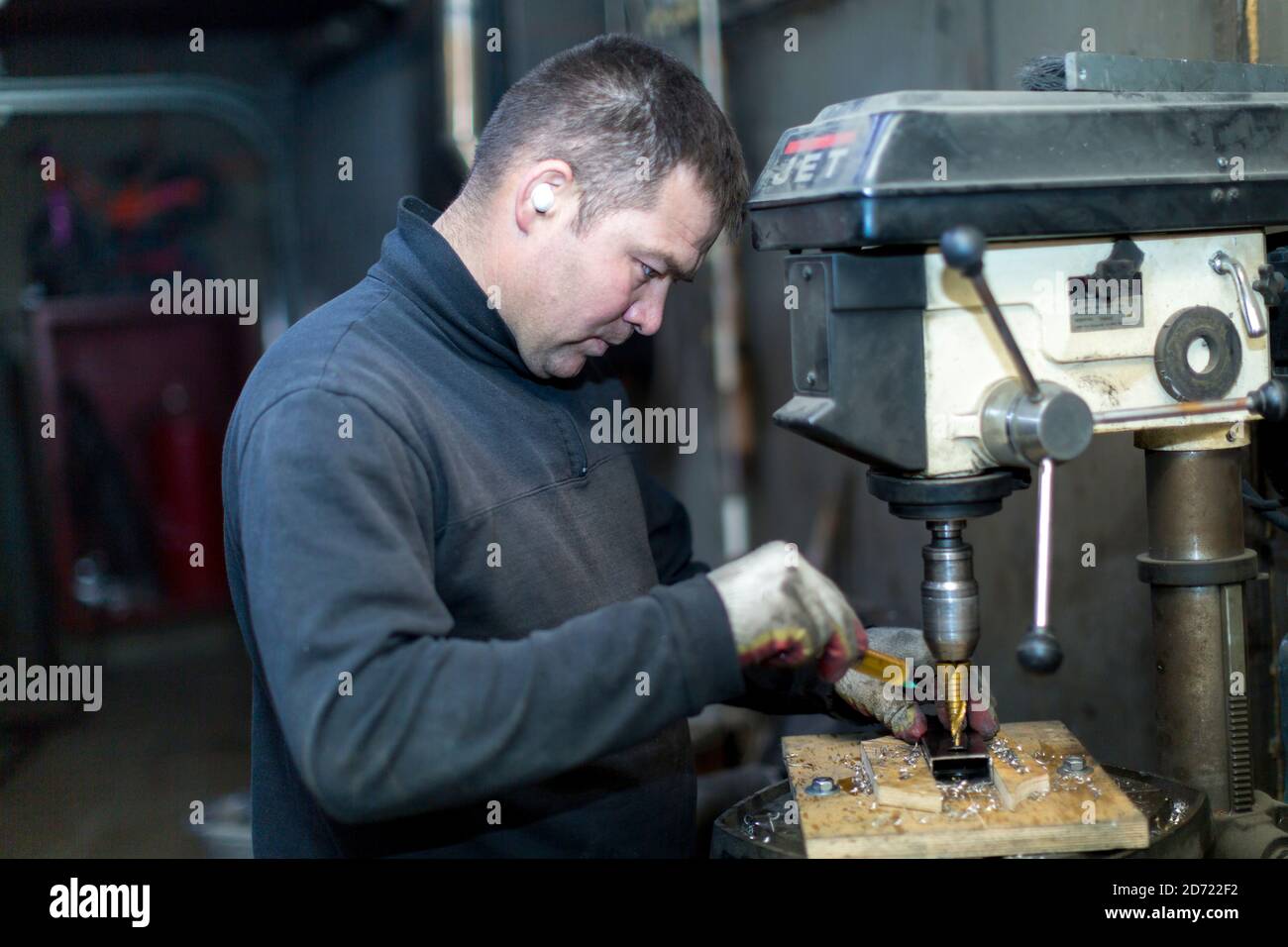 Un lavoratore perfora una parte su una macchina di perforazione Foto Stock