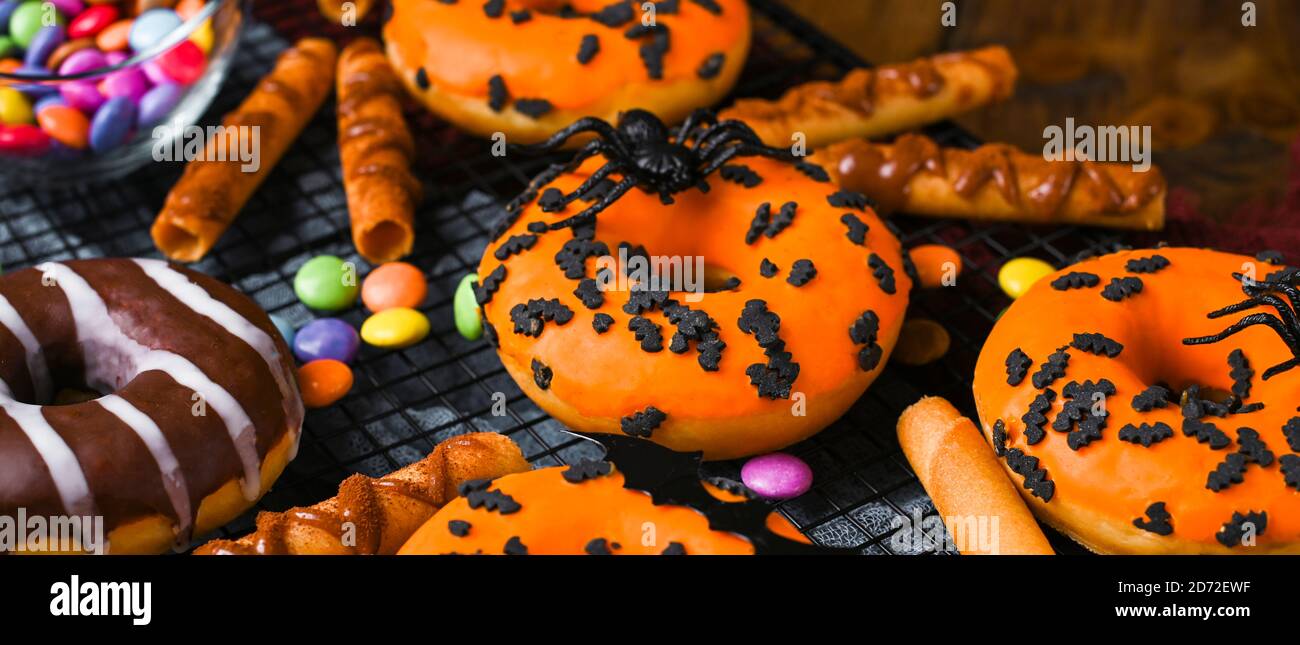 Halloween ciambelle su sfondo di legno. Dolci dolci decorati per una festa horror. Foto Stock