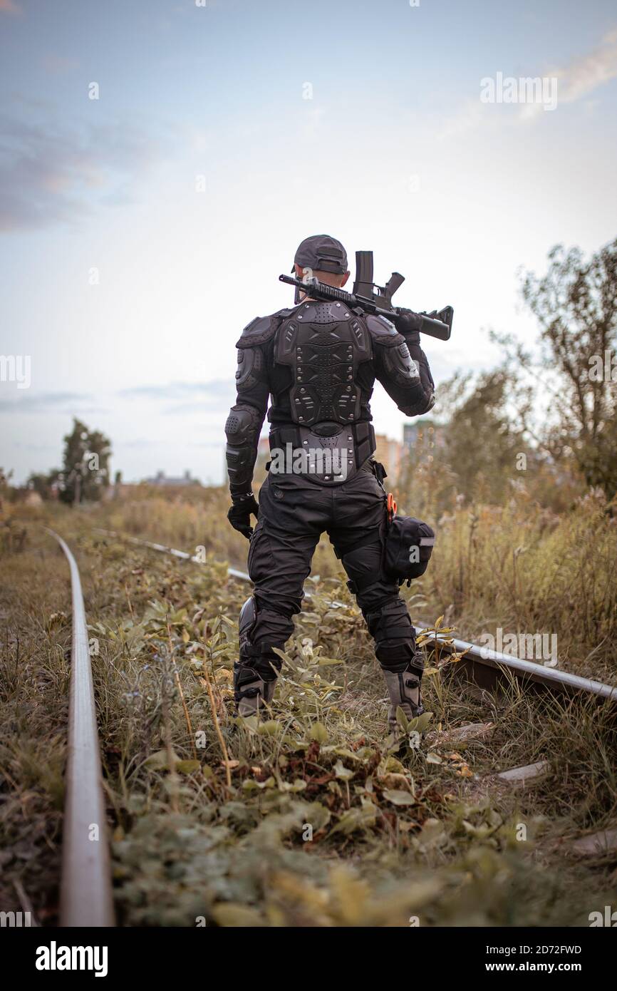 un uomo con un fucile in uniforme si alza con il suo indietro Foto Stock
