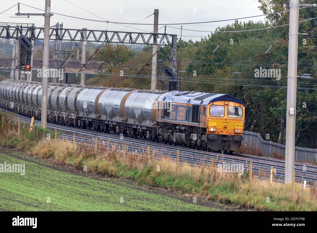 Locomotiva elettrica per il trasporto di merci in deisel classe 66 numero 66776 di GBRF sulla linea principale della costa occidentale che trasporta un treno di cisterne di cemento. Foto Stock