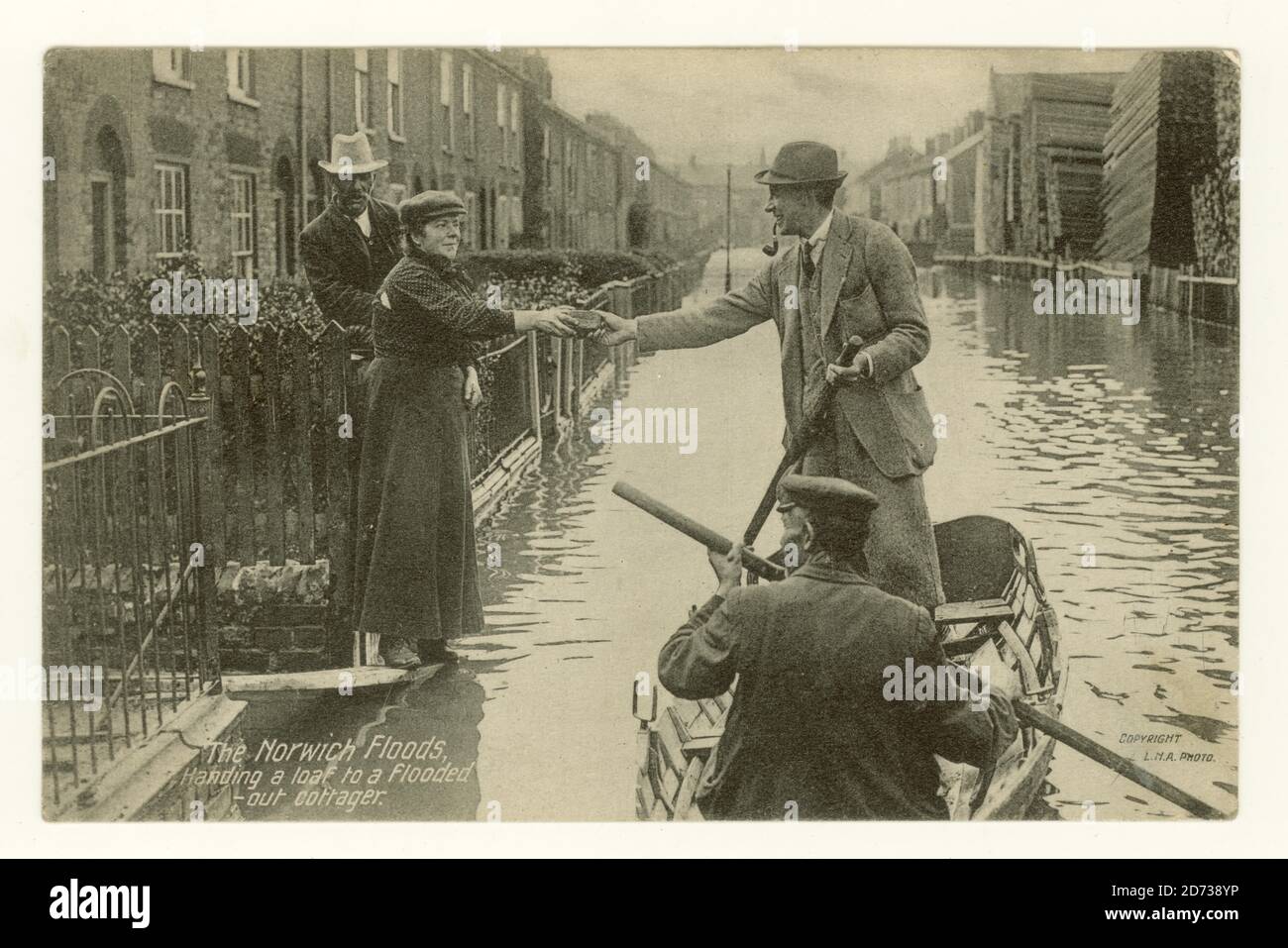 Cartolina dei primi del 1900 di strade allagate a Norwich il 26 agosto 1912 dal titolo "consegna di una pagnotta ad un cotager allagato", Lothian Street con cuscini in legno sulla destra Foto Stock