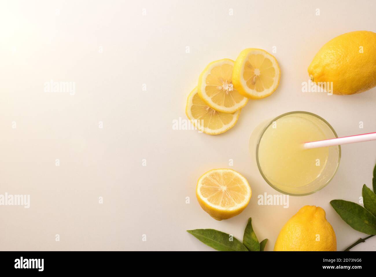 Sfondo con limone organico tagliato e affettato su un tavolo bianco e succo di limone. Vista dall'alto. Composizione orizzontale. Foto Stock