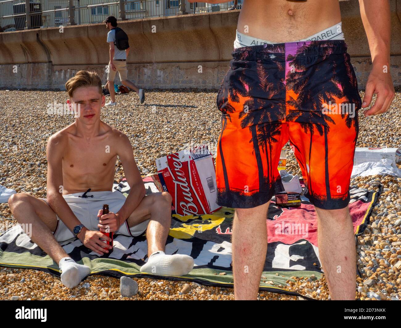 Gli amici potranno gustare una birra al sole in una giornata calda sulla spiaggia di Hastings. Foto Stock