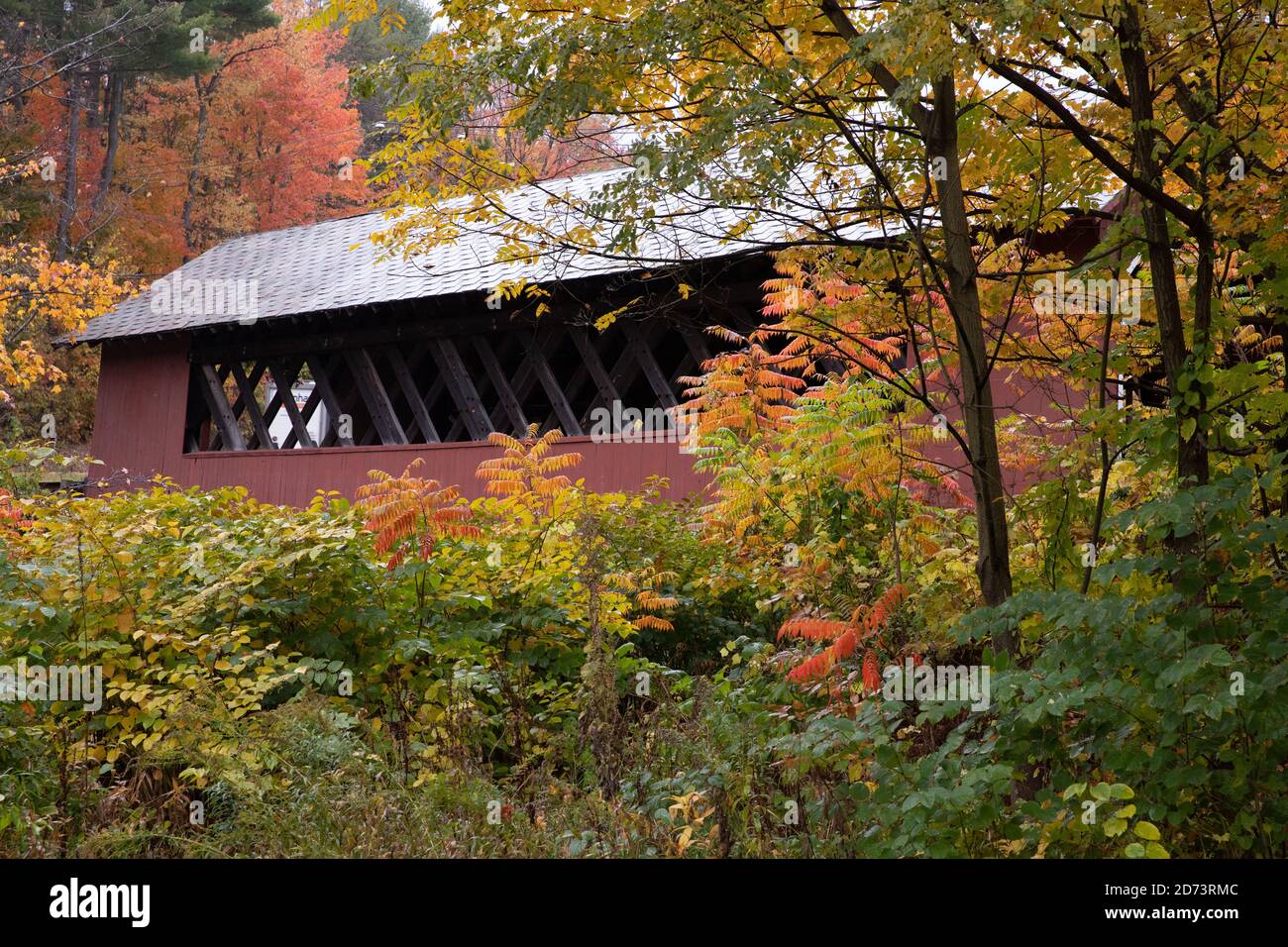 Bellissimo ponte coperto Vermont circondato da colorate foglie autunnali. Foto Stock