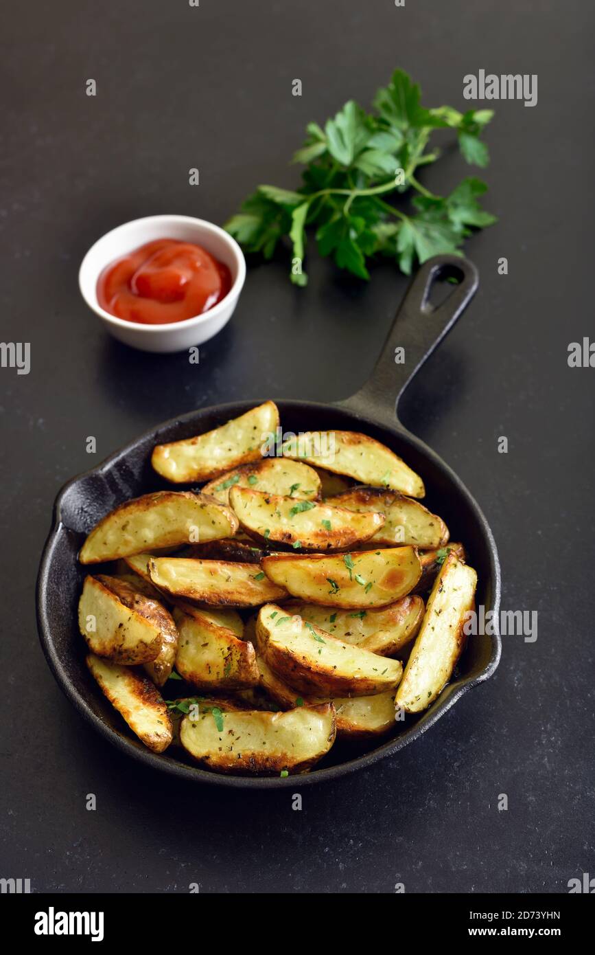 Fette di patate fritte in padella su fondo di pietra nera Foto Stock