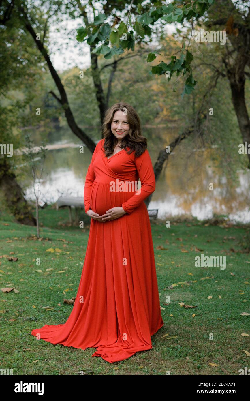 Donna in un vestito rosso per le foto di maternità Foto Stock