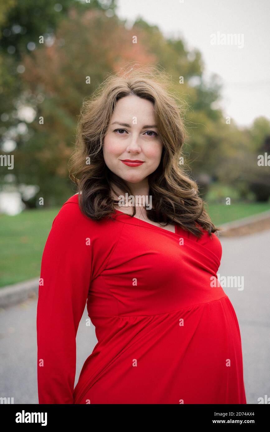 Donna in un vestito rosso per le foto di maternità Foto Stock