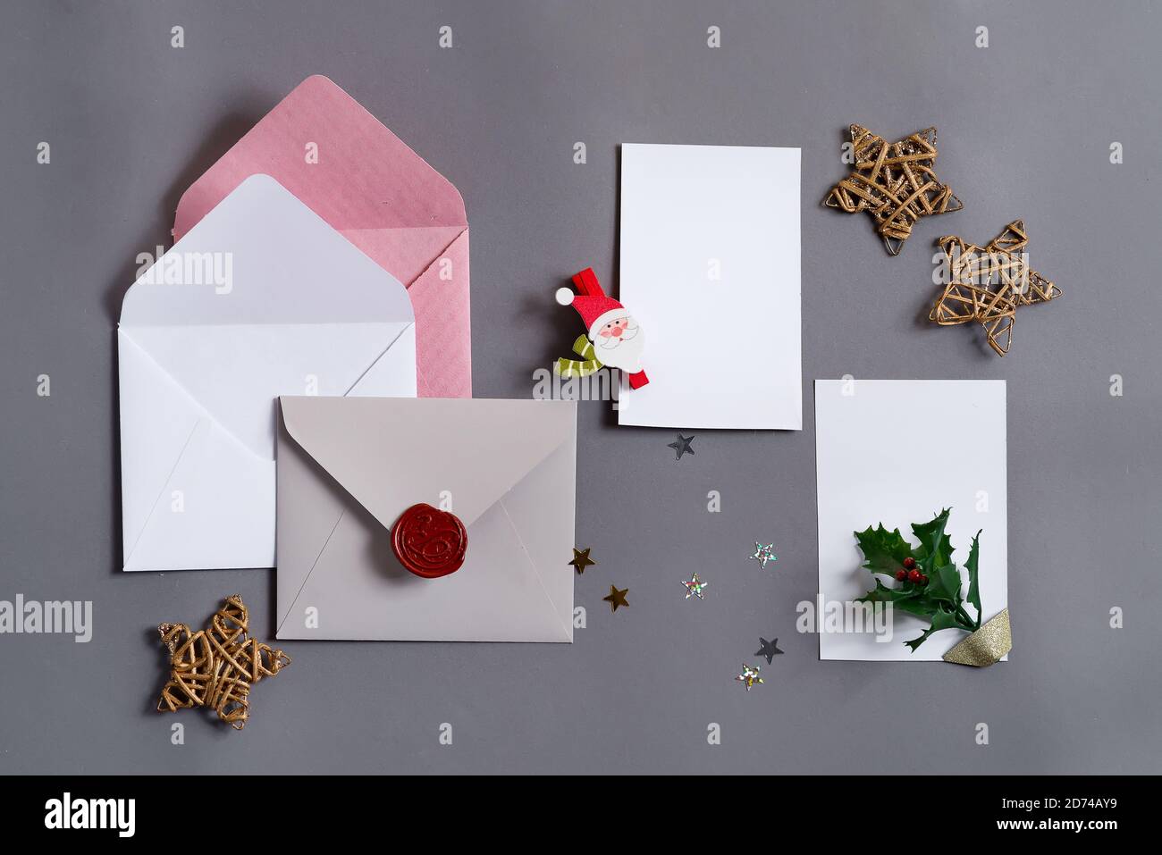 Sfondo festoso da carte di carta mock-up colorate con buste e decorazione di Natale su uno sfondo grigio, spazio di copia. Cartolina di benvenuto. Foto Stock