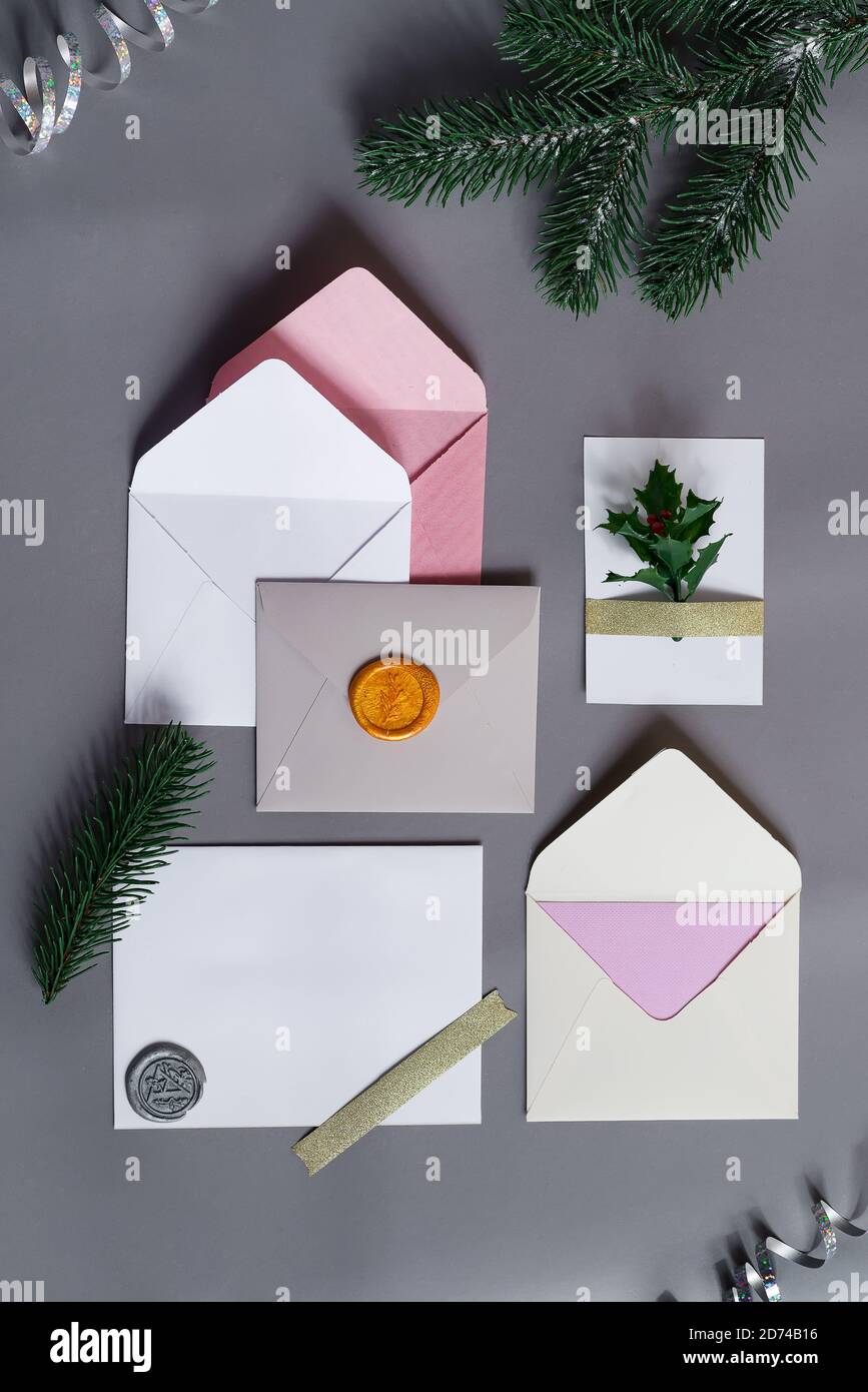Sfondo festoso da carte di carta mock-up colorate con buste e decorazione di Natale su uno sfondo grigio, spazio di copia. Cartolina di benvenuto. Foto Stock