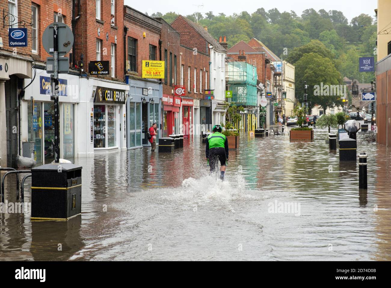 Winchester, Inghilterra ,UK 27/08/2020 UN ciclista che corre attraverso l'acqua di alluvione sulla High Street a Winchester dopo pesanti downpoours a causa della tempesta Francis. Foto Stock