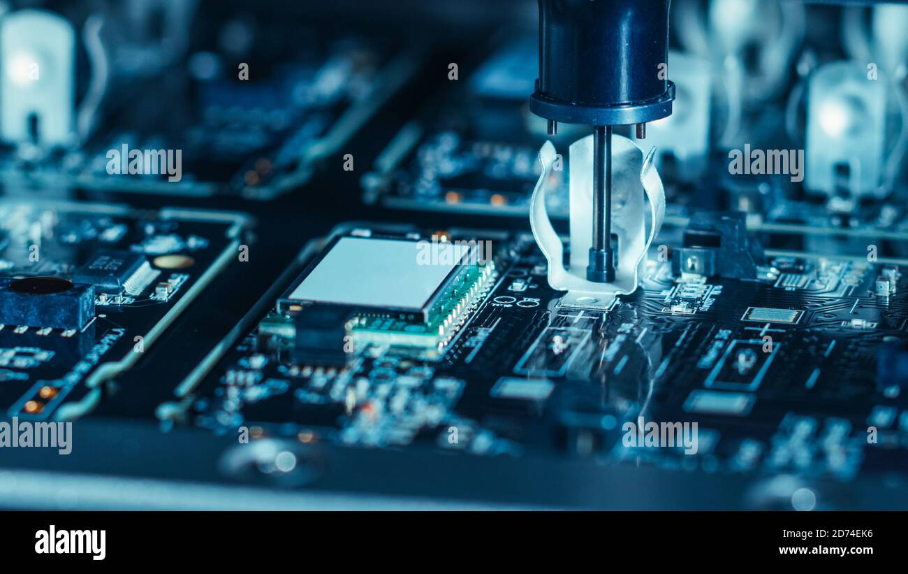 Close-up Macro Shot della macchina elettronica in fabbrica al lavoro: Scheda a circuito stampato in fase di assemblaggio con braccio robotizzato automatizzato, posiziona supporti tecnologici Foto Stock