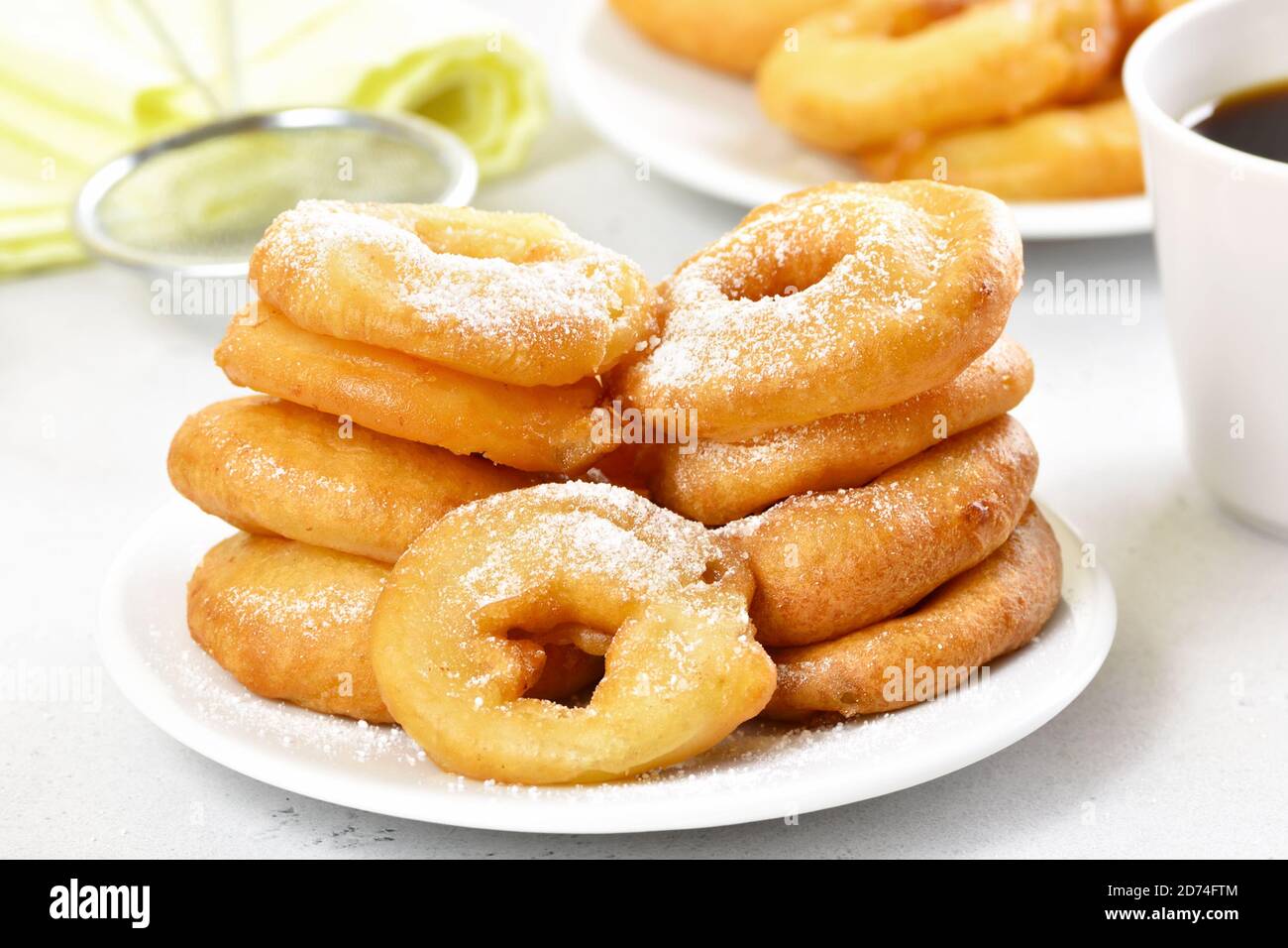 Ciambelle fatte in casa con zucchero in polvere su piatto bianco, vista ravvicinata Foto Stock